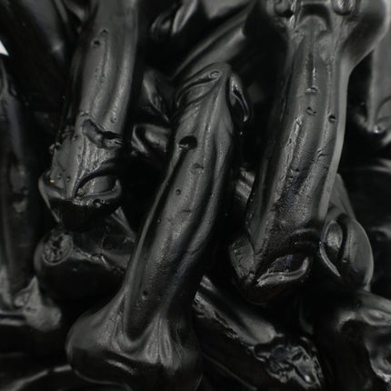 Close-up of black licorice drop candies shaped like bones, glossy finish
