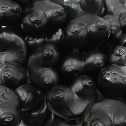 Black licorice candies with glossy finish in playful shapes, bulk confectionery close-up.
